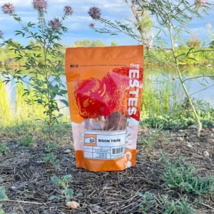 A bag of meal worms placed outdoors on the ground near water and trees.